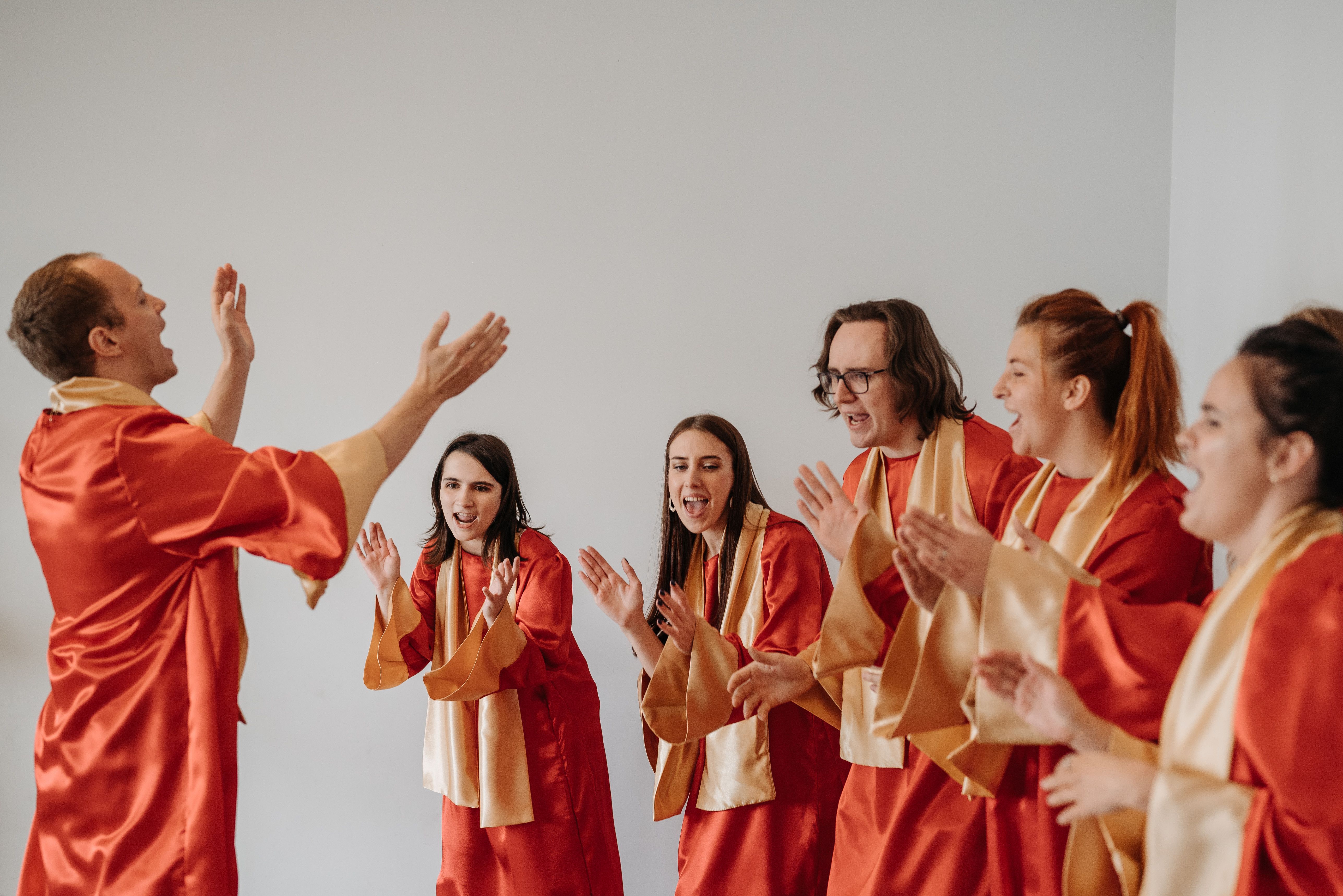 A church choir in orange and white uniform clapping while singing