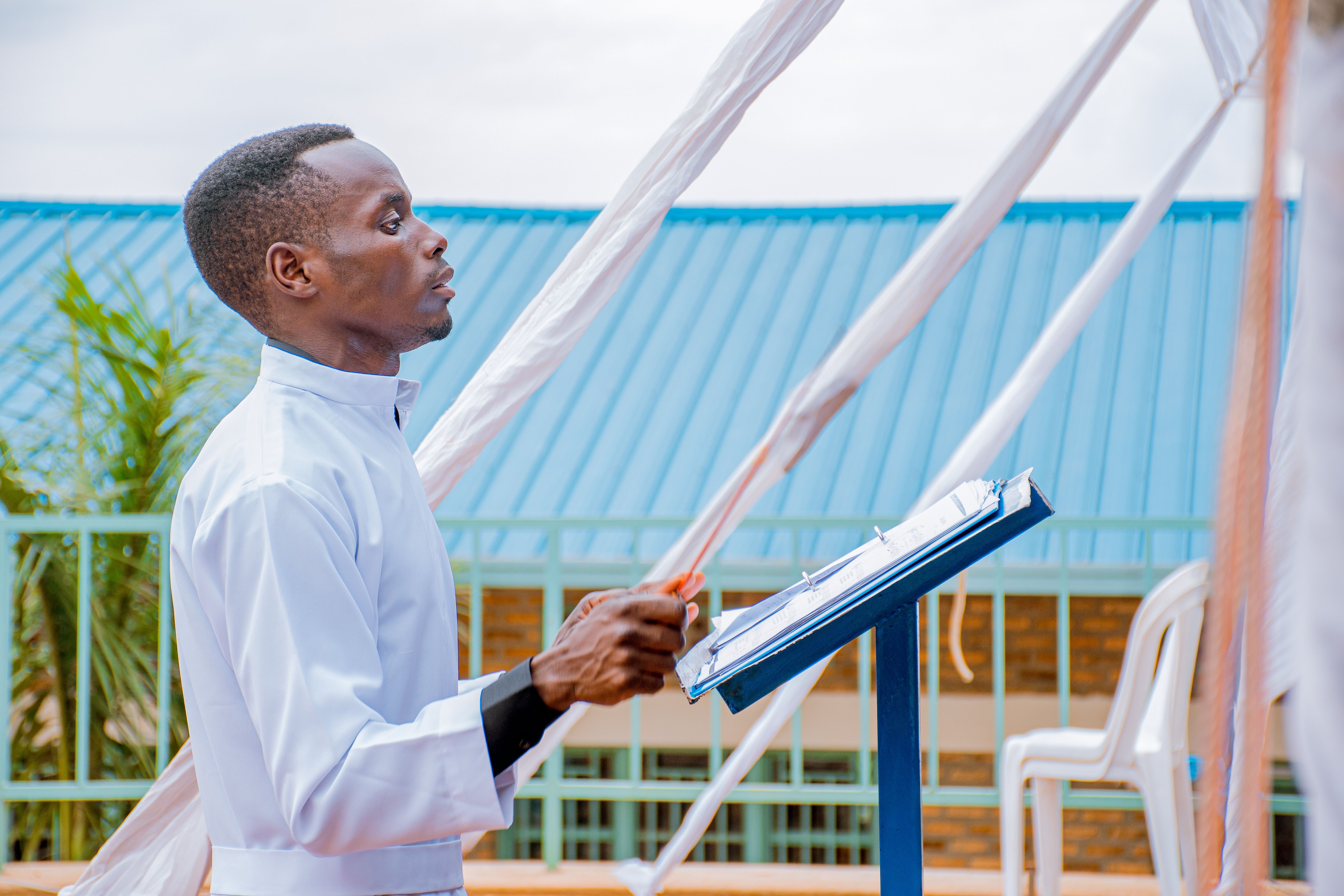 Clergy member in clerical attire speaking to a crowd outdoors