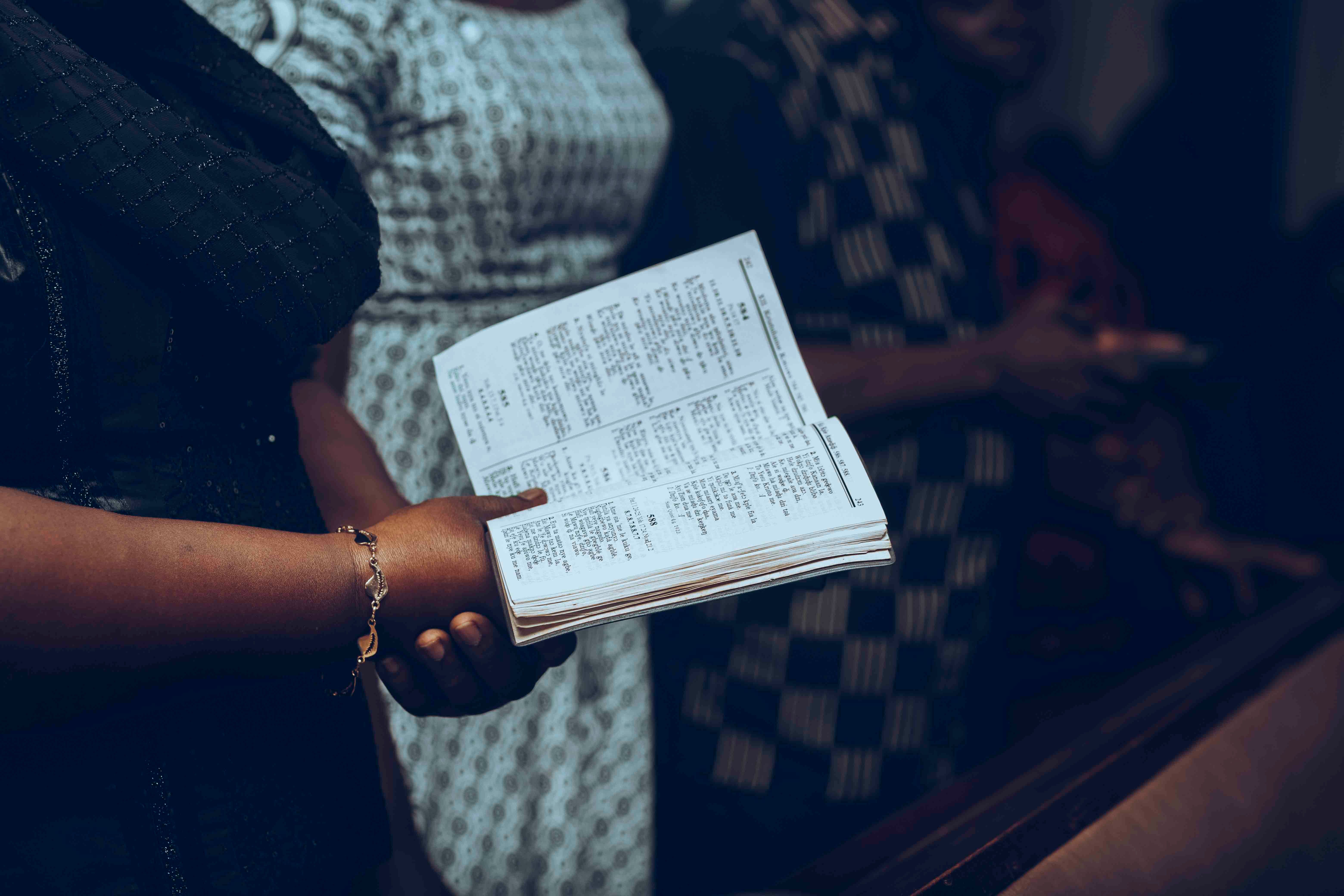 A diverse congregation holding hymn books during worship