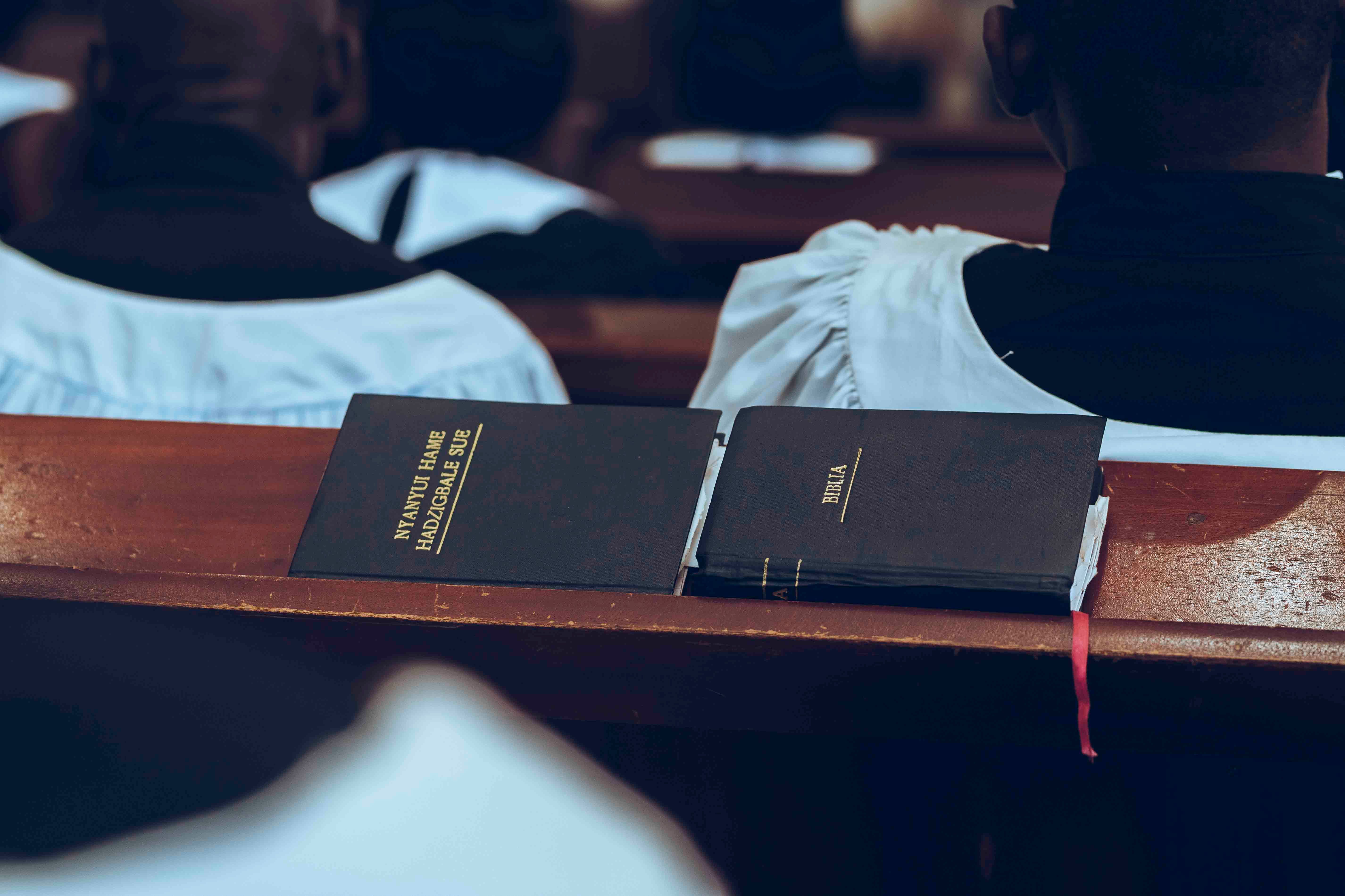 A hymn book and bible in close focus inside a church