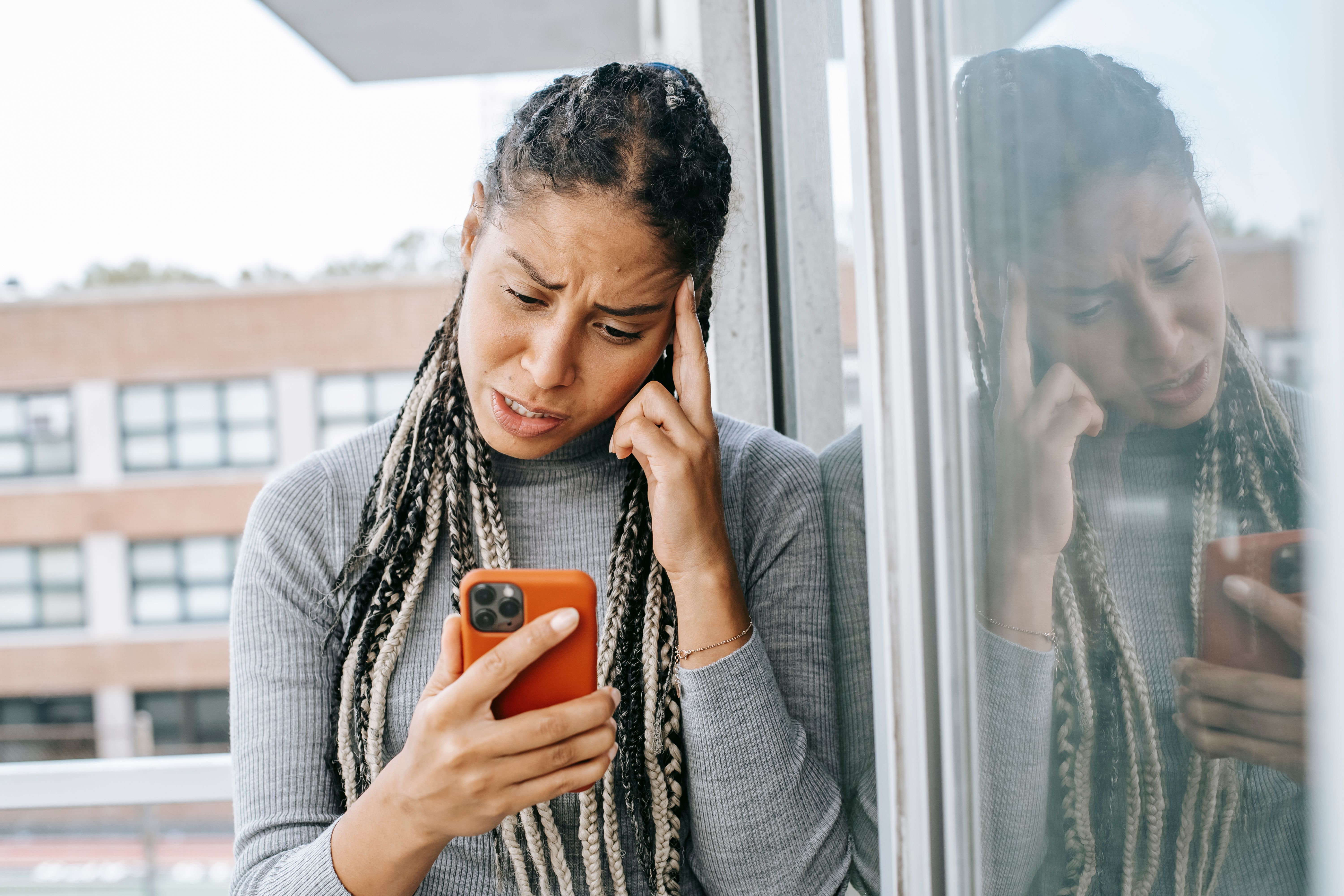 A tired woman looking at her phone with a weary expression